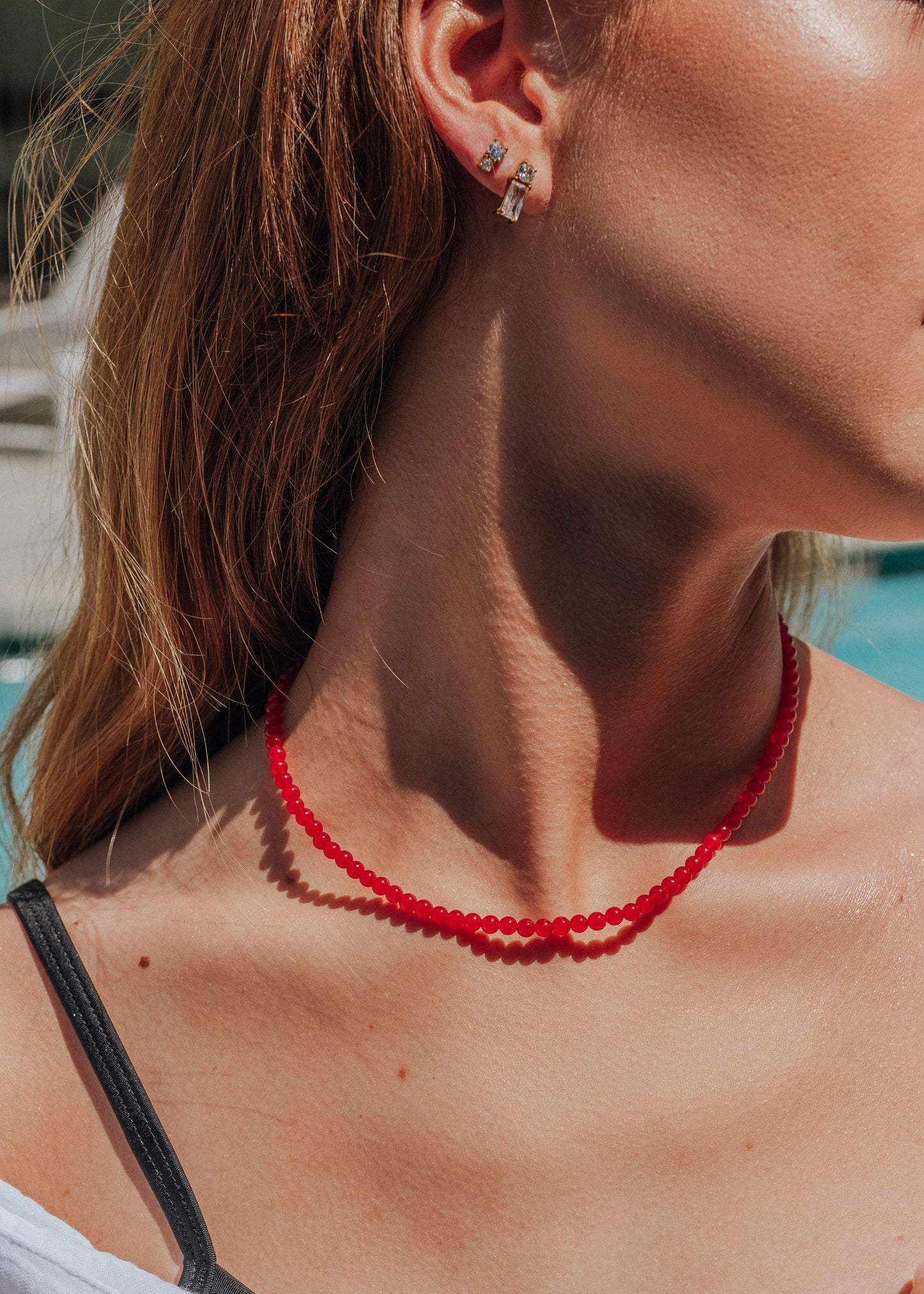 Close-up of a person wearing a red beaded necklace and earrings.