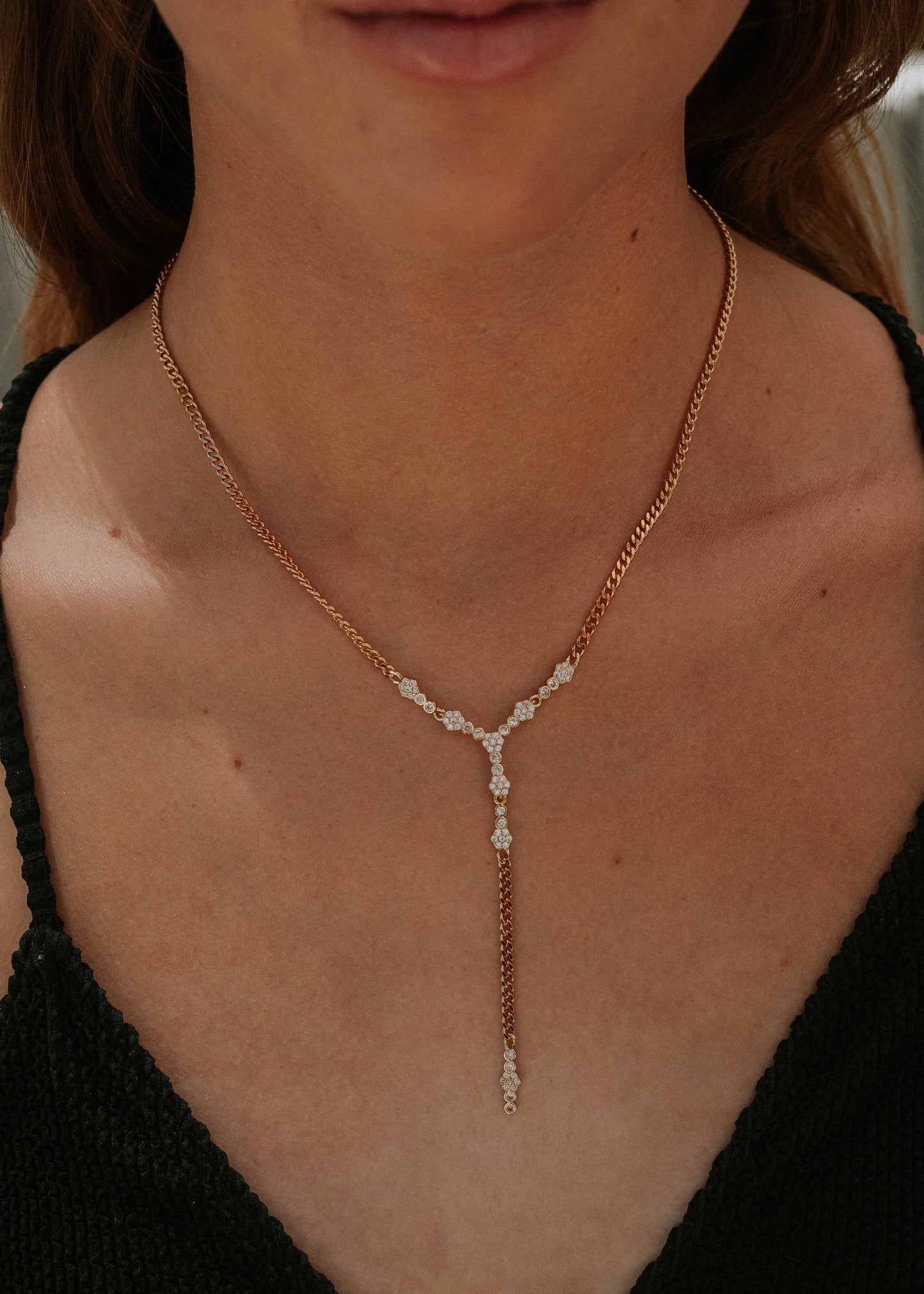Close-up of a person wearing a delicate gold necklace with a black top.
