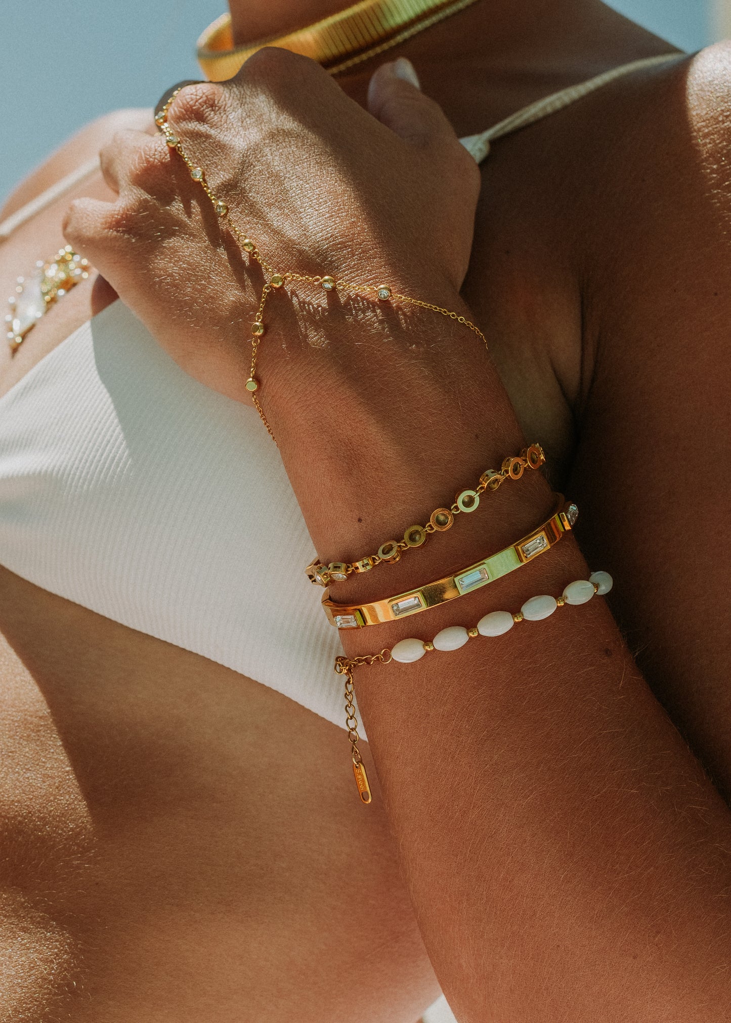 Close-up of a person's arm with multiple gold bracelets on a blurred background