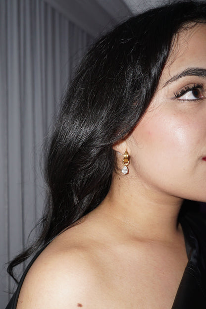 Close-up of a woman wearing gold diamond charm earrings