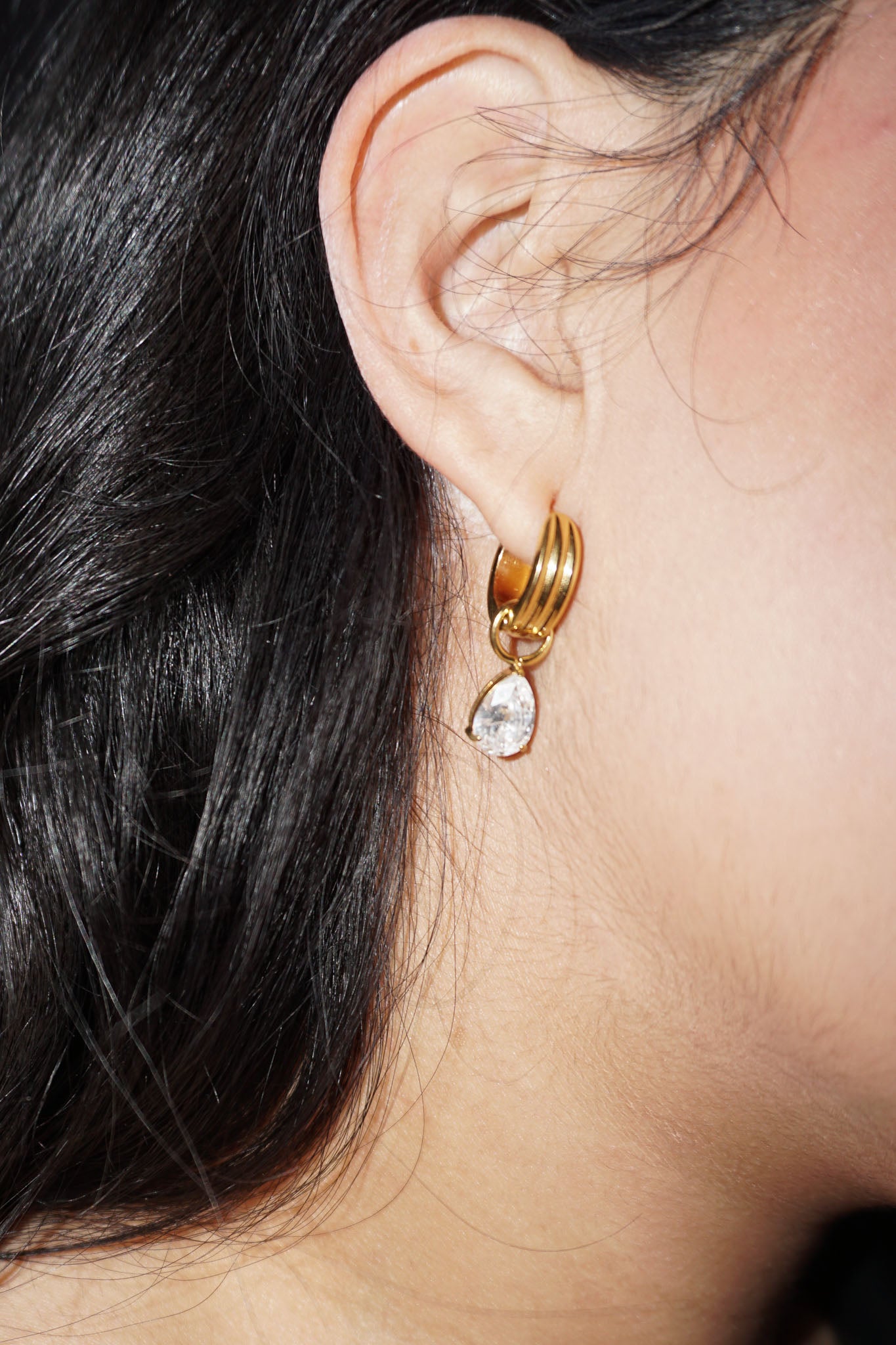 Close-up of a woman wearing gold diamond charm earrings