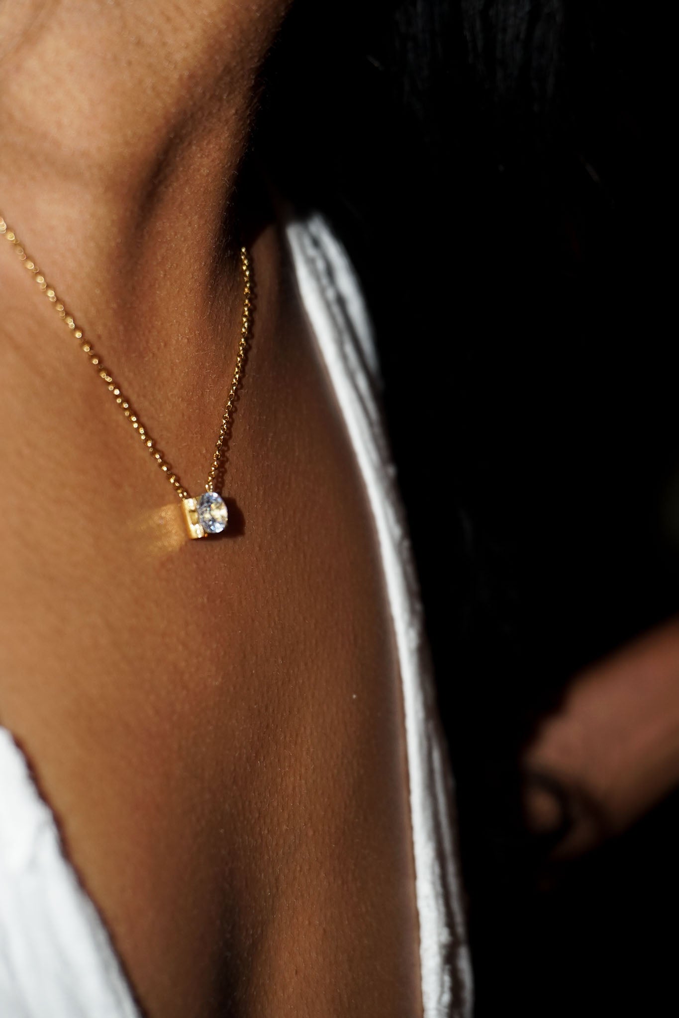 Close-up of a gold necklace with a small pendant on a person's neck.
