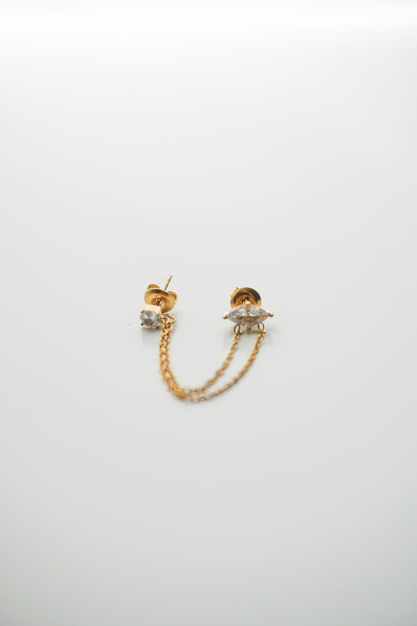 Gold chain earrings on a light gray background