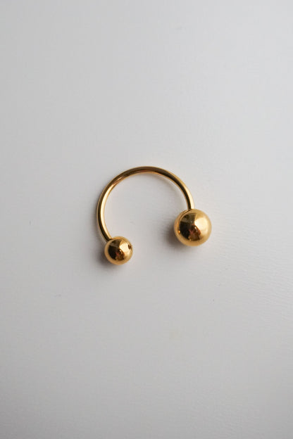 Gold hoop earring with spherical ends on a light gray background