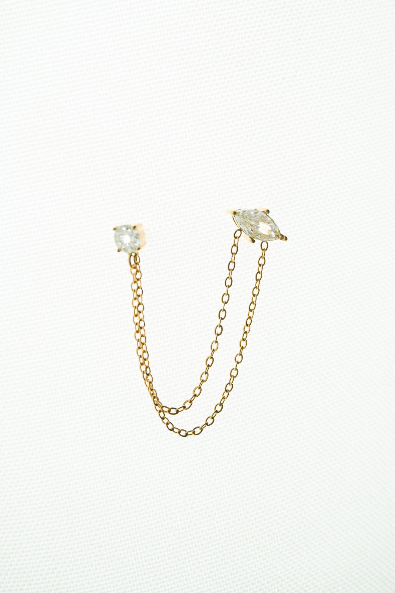 Gold chain earrings with clear gemstones on a white background