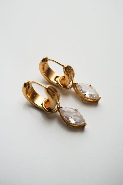 Gold hoop earrings with clear gemstones on a light gray background