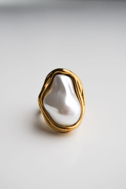 Gold ring with a large white stone on a light gray background