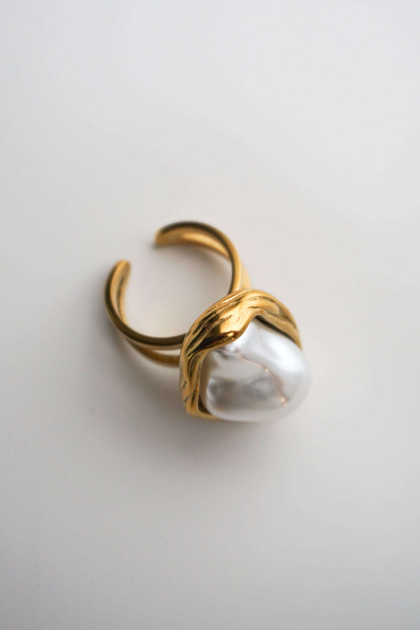 Gold ring with a large pearl on a light gray background