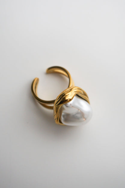 Gold ring with a large pearl on a light gray background