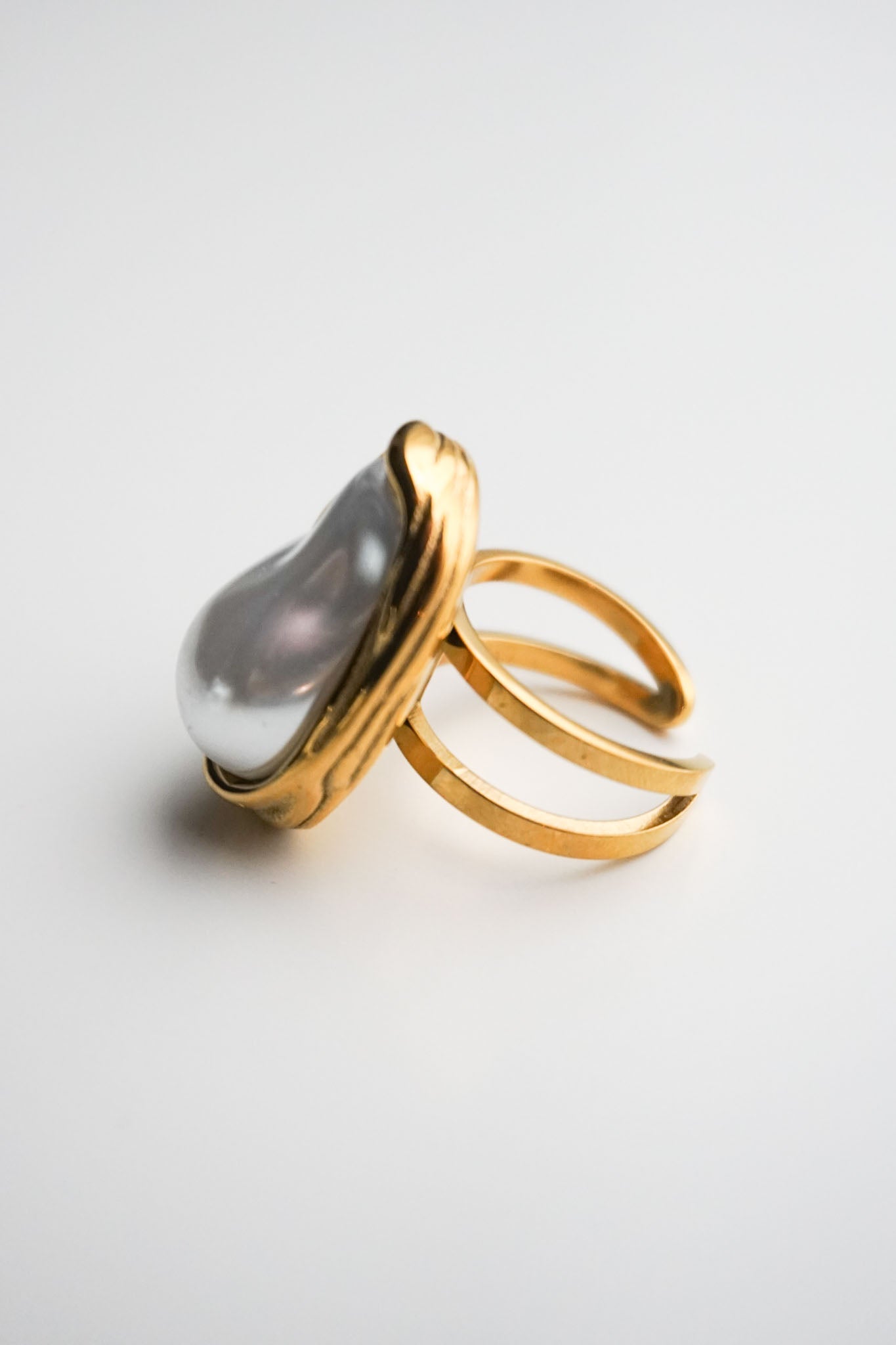 Gold ring with a large gray gemstone on a light gray background