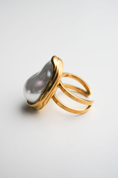 Gold ring with a large gray gemstone on a light gray background