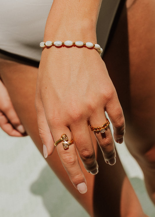Hand wearing a bracelet and multiple rings with a blurred background
