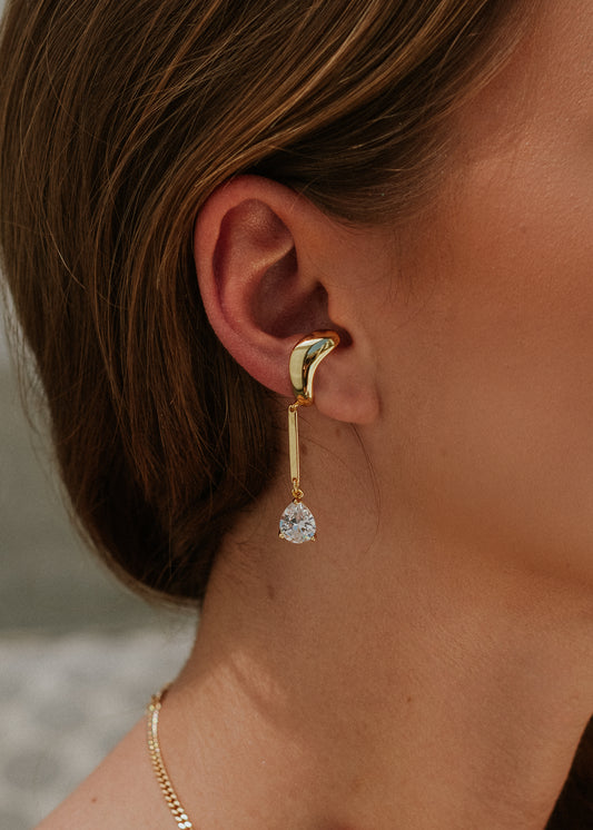 Gold earring worn by a person with a blurred background