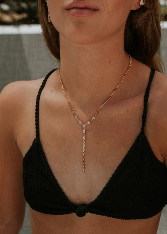 Woman wearing a black bikini top with a gold necklace.