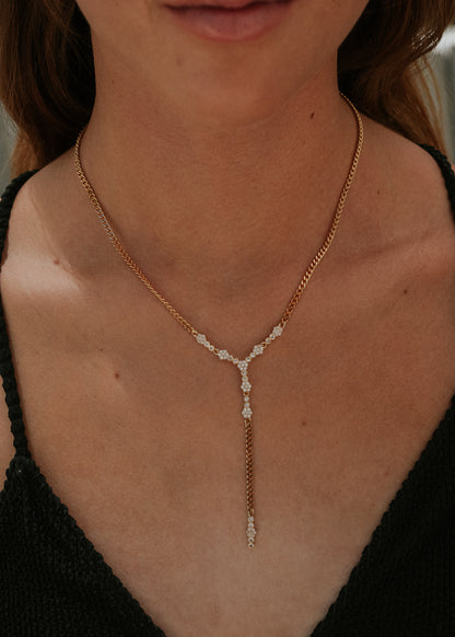 Close-up of a person wearing a delicate gold necklace with a black top.