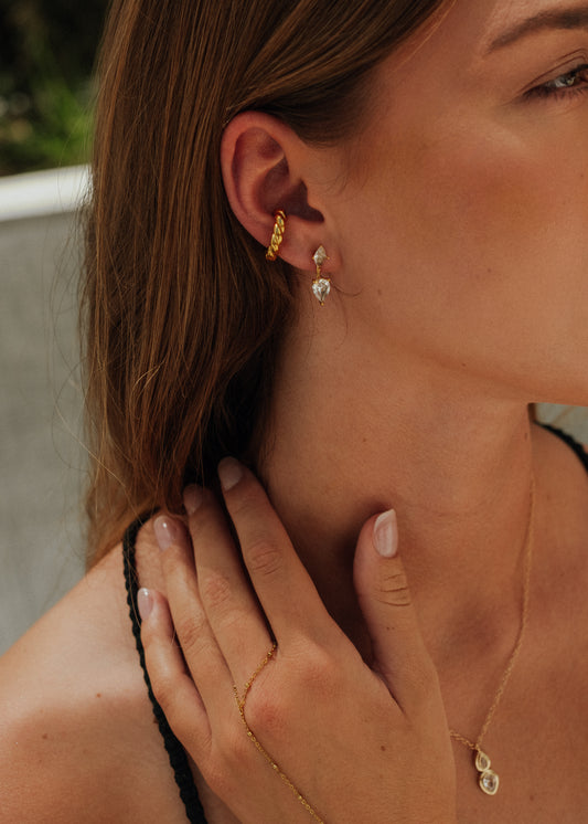 Close-up of a woman wearing gold hoop earrings with a blurred background